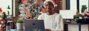 person at laptop with christmas tree in the background