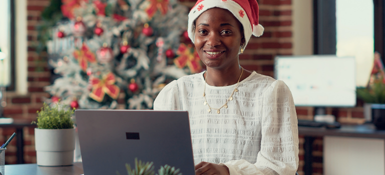 person at laptop with christmas tree in the background