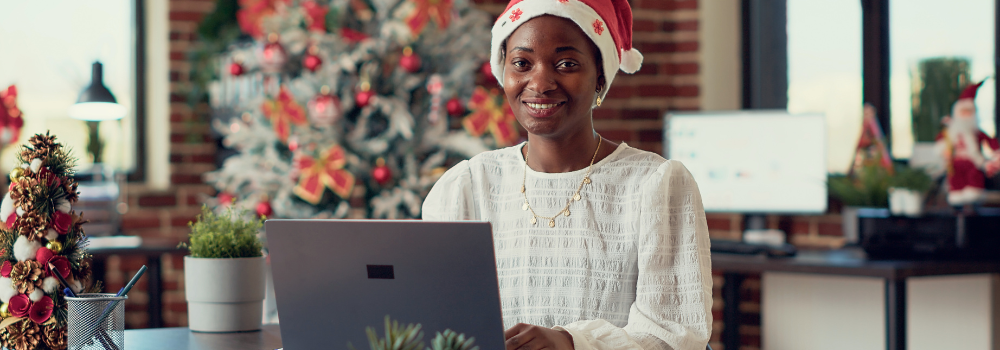 person at laptop with christmas tree in the background